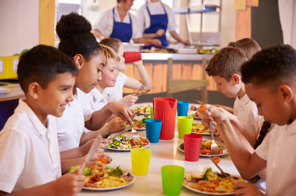 students dining in a cafeterial with their school lunches