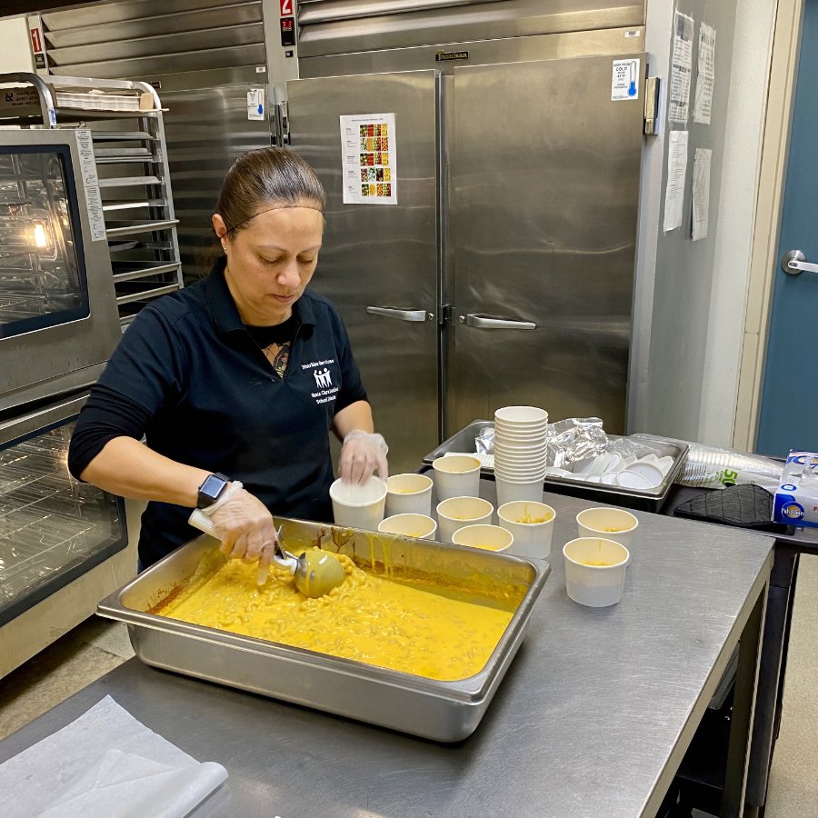 Gabby Flores scoops mac and cheese in the school cafeteria at Scott Lane Elementary in Santa Clara. (Photo credit: Anne Marshall-Chalmers)