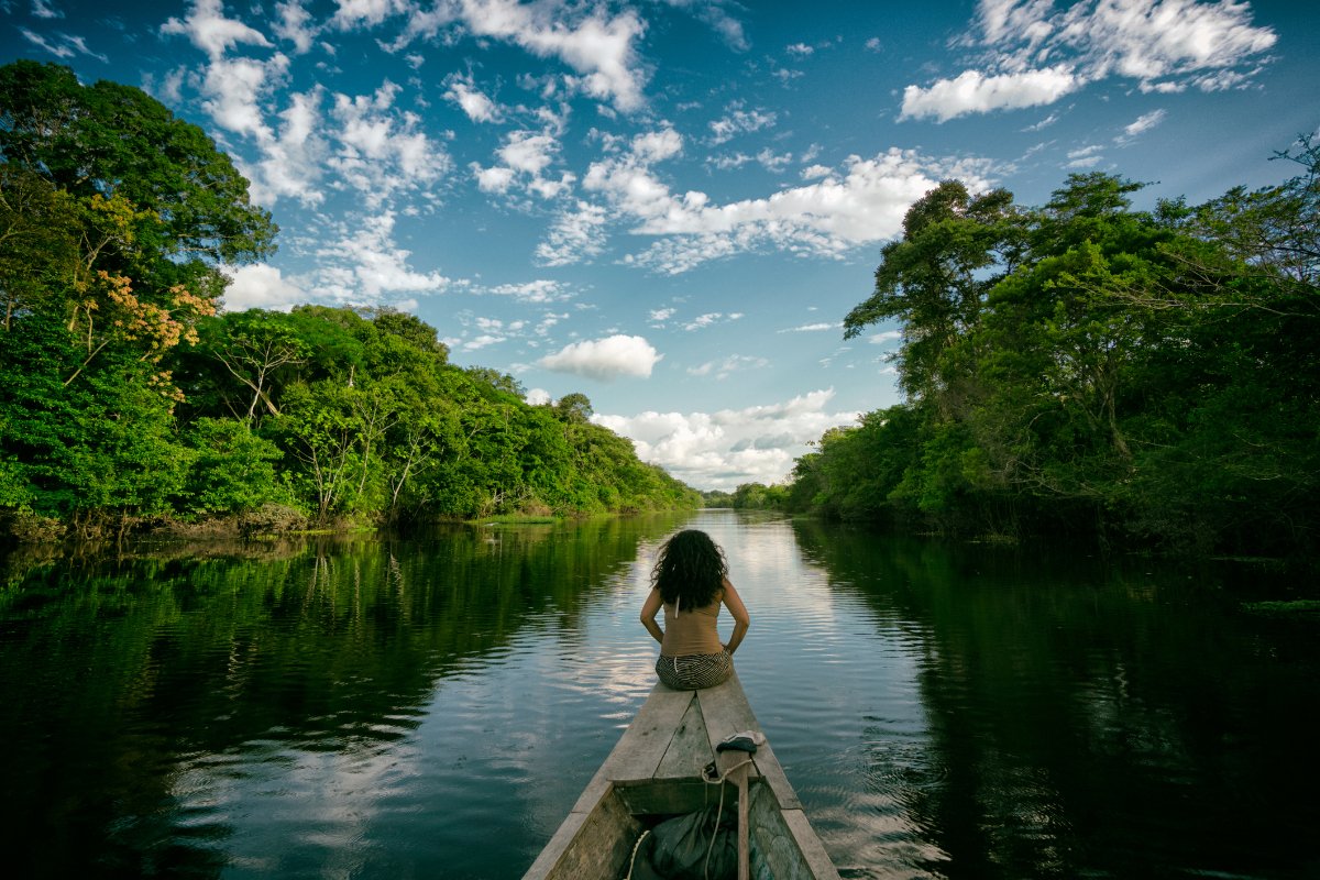 Sailing in a wooden boat on the Amazon river in Peru. An indigenous girl sitting on the front of the boat whilst sailing down the river.