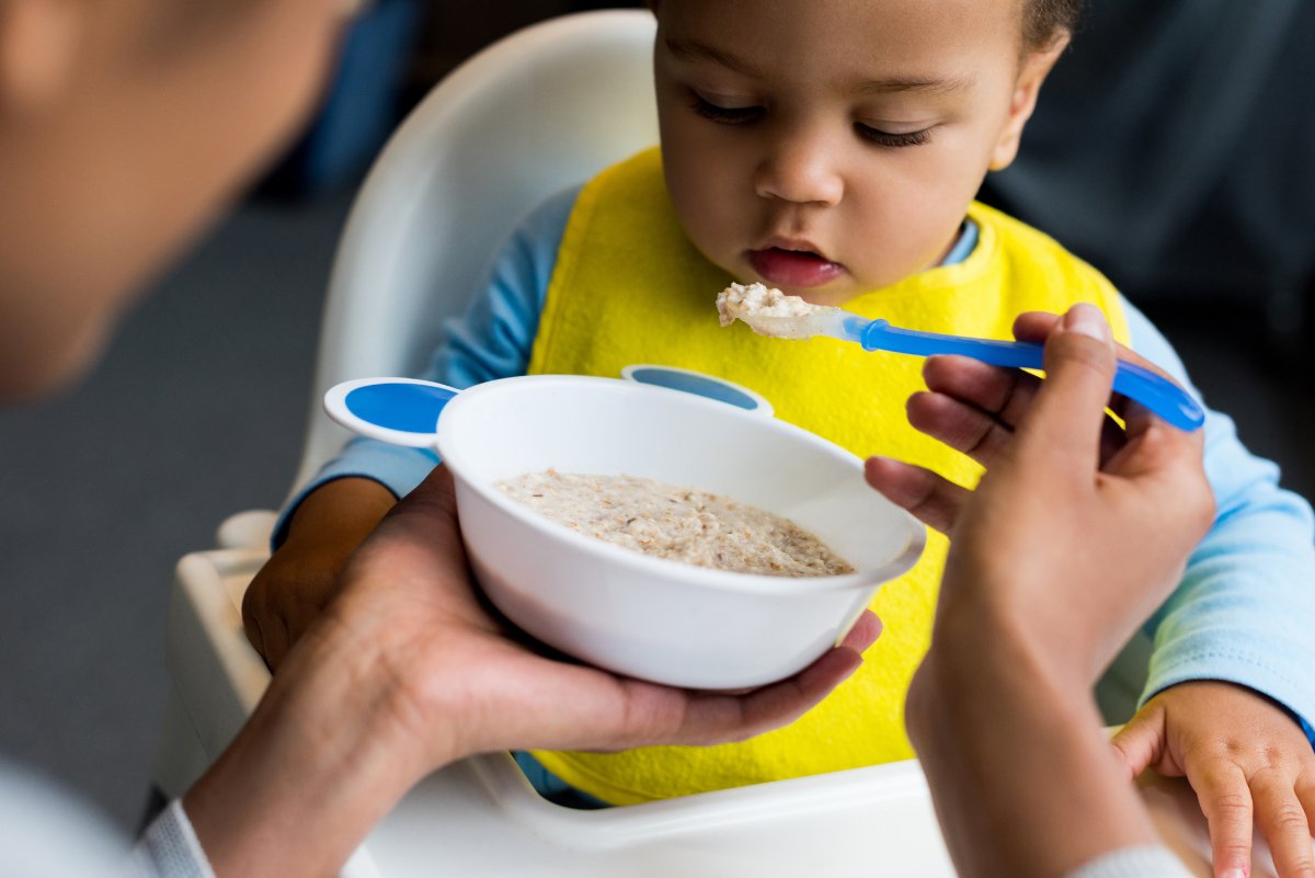 A young parent feeds an infant food that they bought using their WIC benefit.
