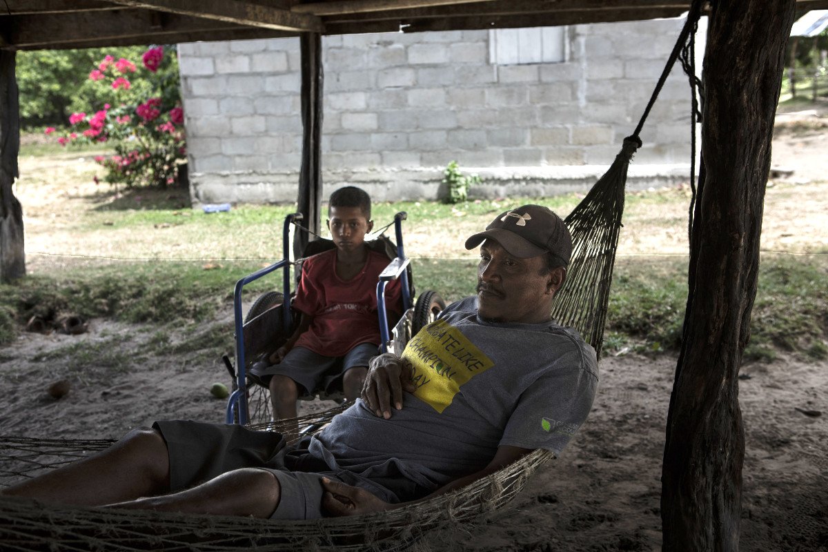 Nixon González Flores, 55, is a diver paralyzed from the waist down. His youngest son sits in his wheelchair. (Photo credit: Jacky Muniello)