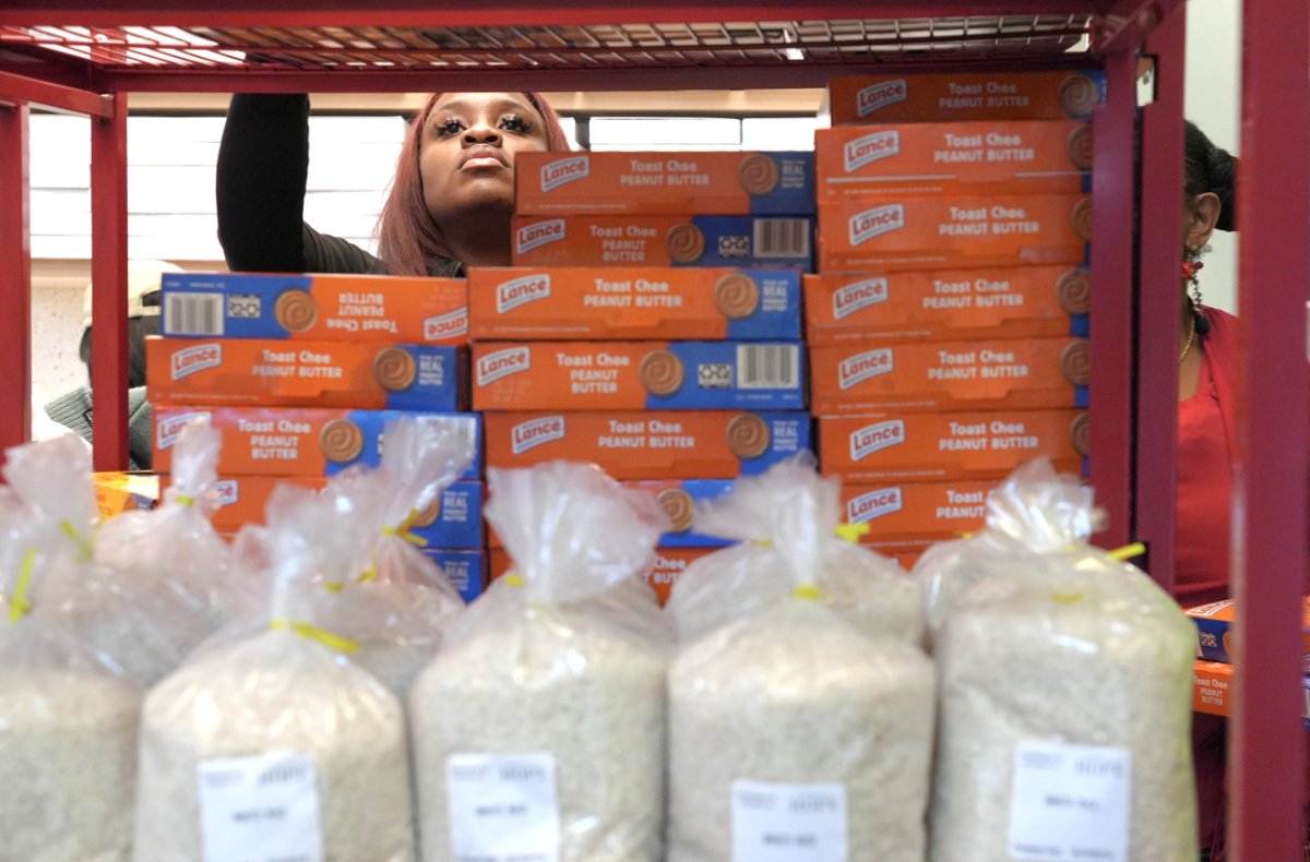 Raquel Cureton, a program assistant at Pratt Library, helps with the Pratt Free Market. (Photo credit: Sam Delgado) standing in front of rows and bags of white rice