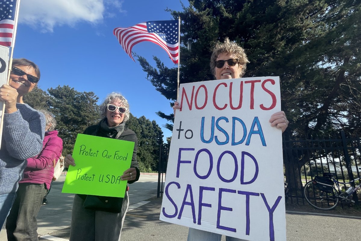 Three protestors hold signs saying